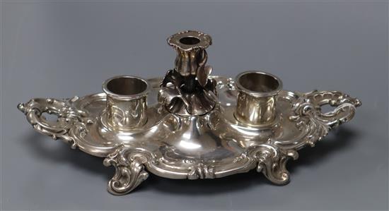 An ornate Victorian silver shaped oval inkstand, with taperstick, Birmingham,1842 and two later associated silver wells, 22cm.